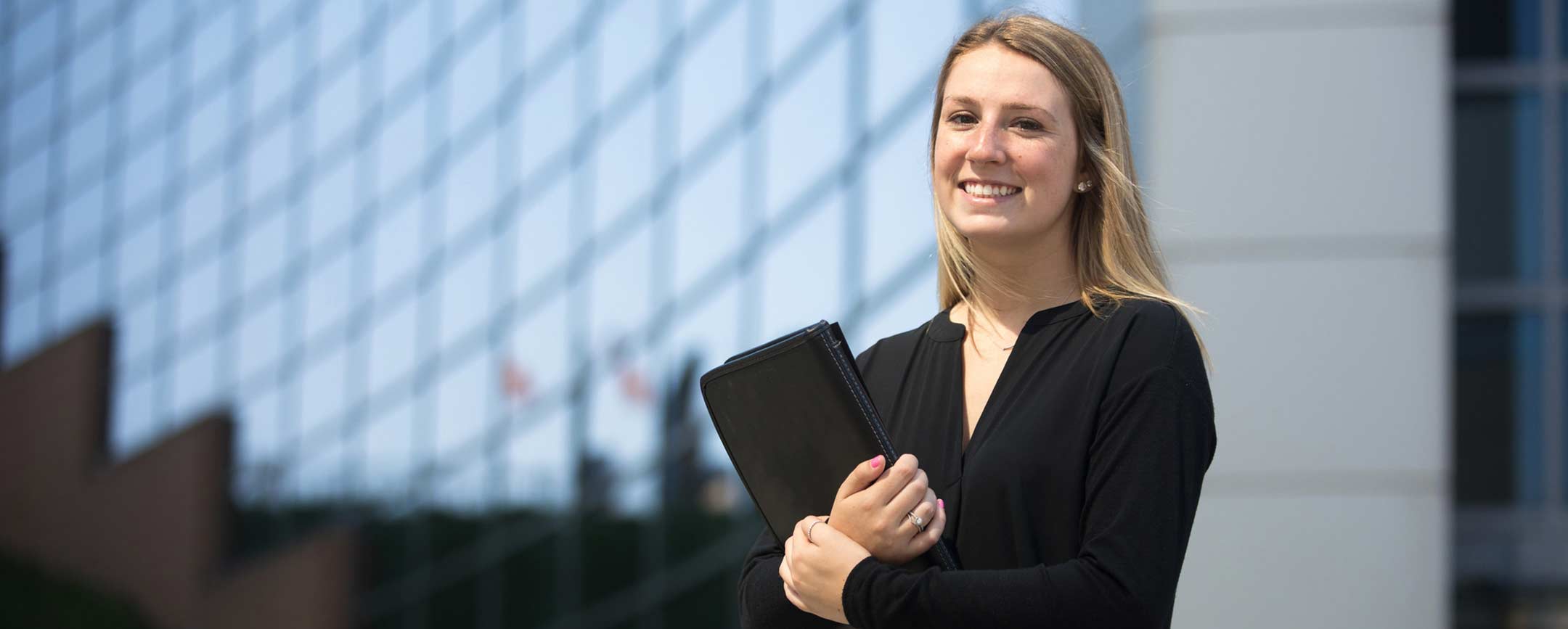 A graduate student holding a business portfolio