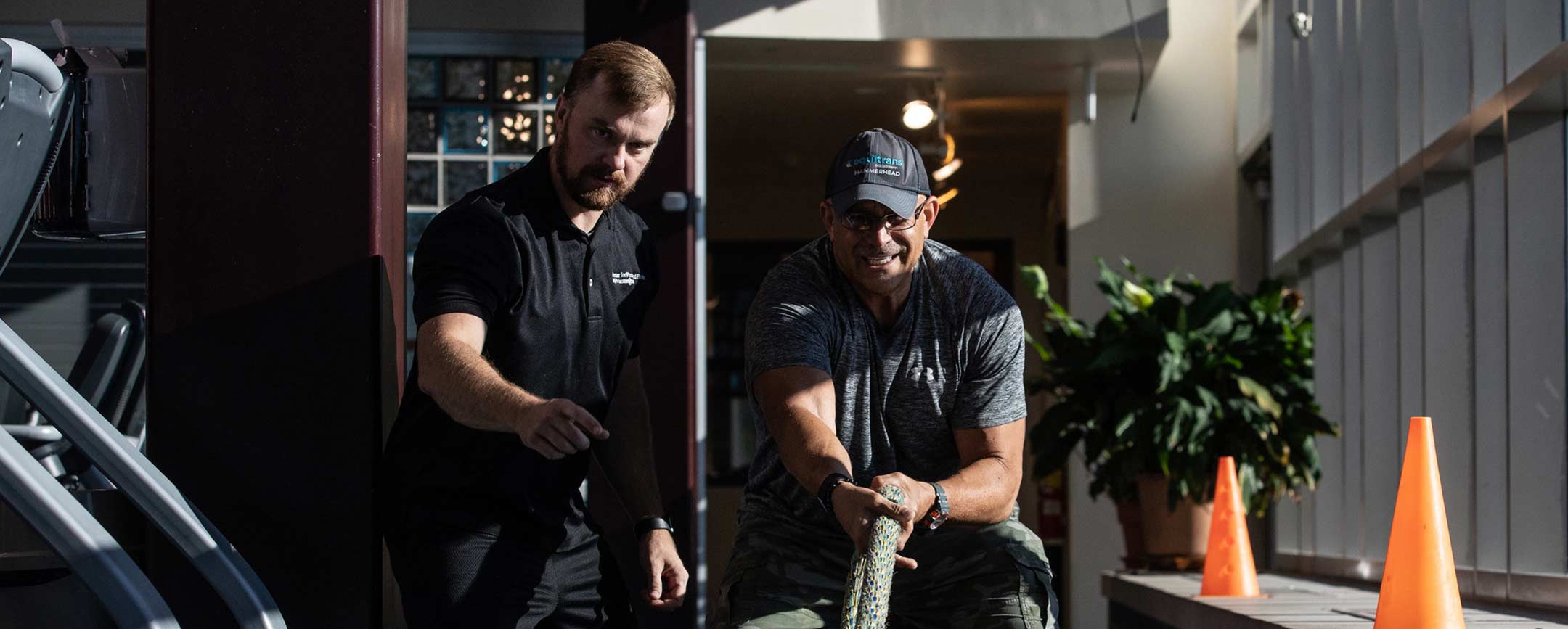 A trainer is observing a client who is training with ropes.