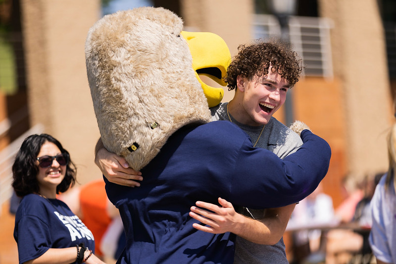 The Clarion Golden Eagle mascot hugs a student.