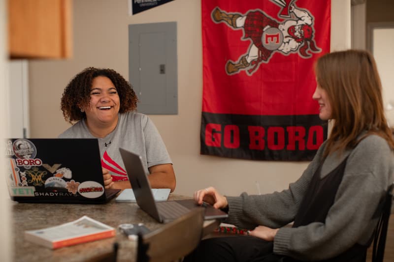 Students studying and laughing in a dorm room at PennWest Edinboro. 