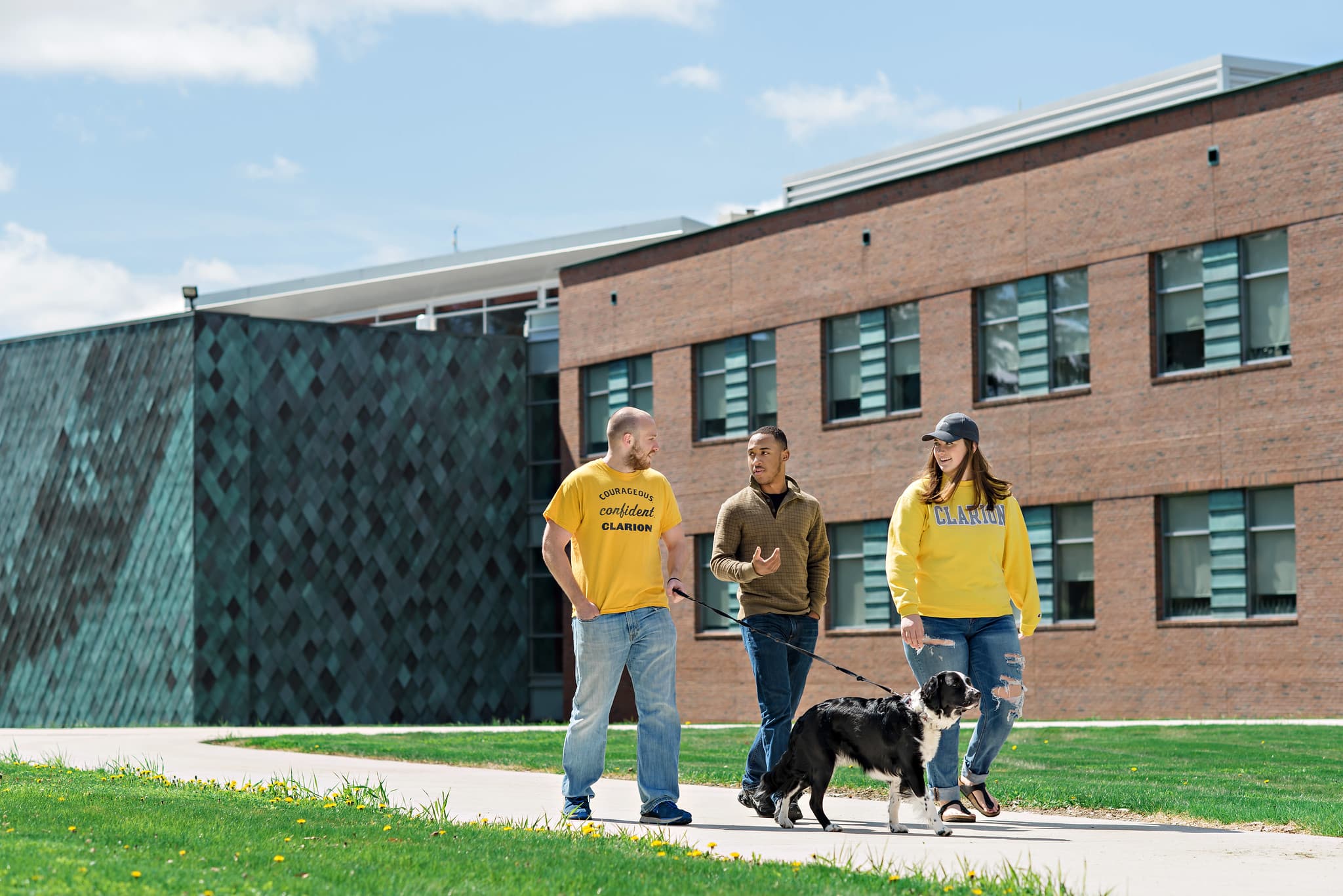 Students walking a dog on the campus of PennWest Clarion.