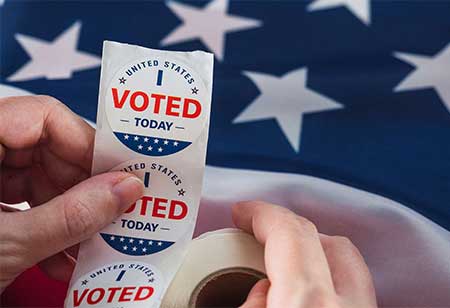 An american flag with a person holding voting stickers