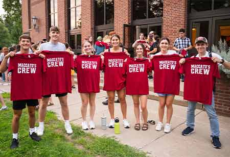 Students holding "MacCato's Crew" shirts