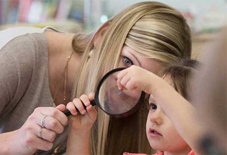 A teacher and student looking through a magnifying glass