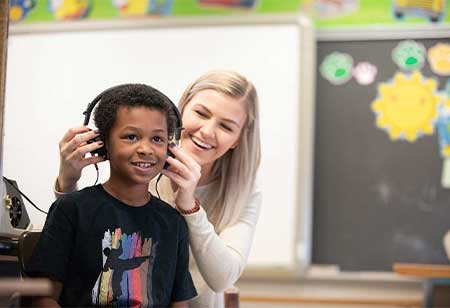 A hearing professional putting headphones on a child