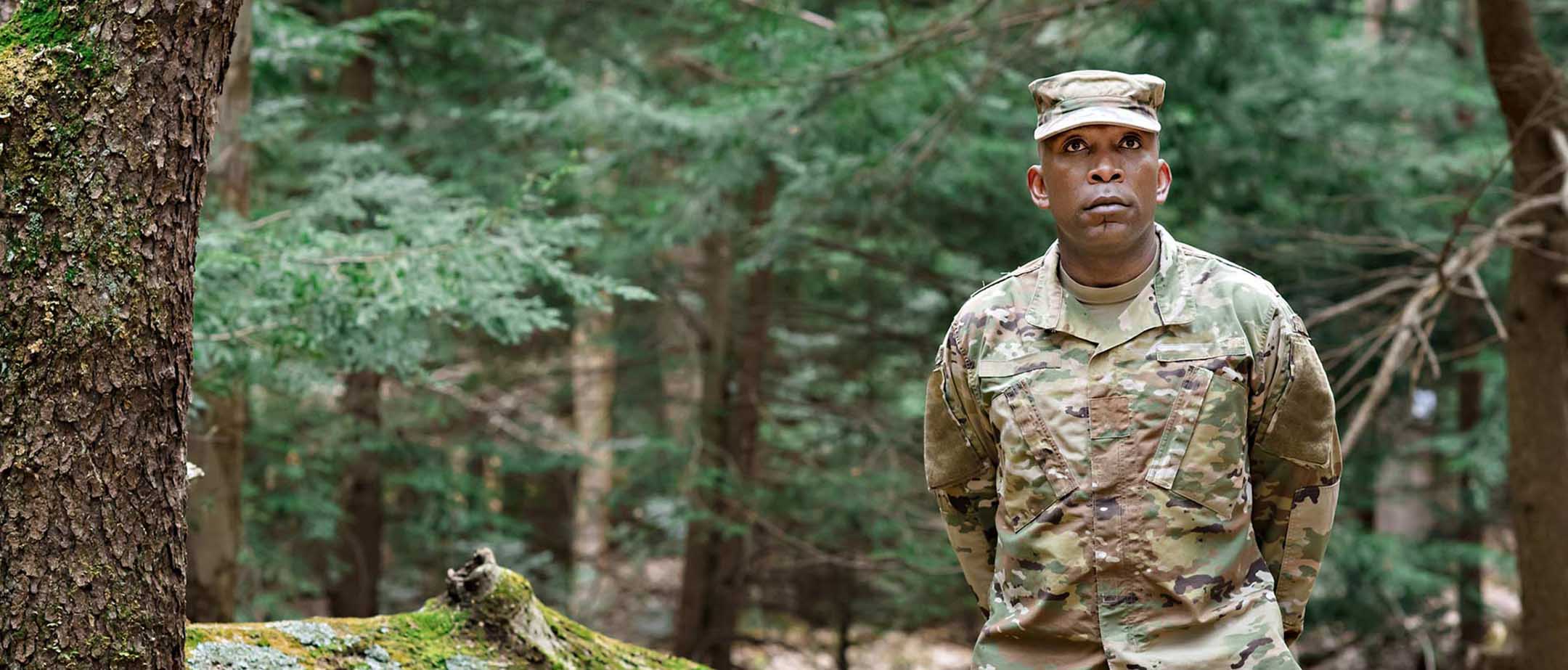 Image of soldier in camo in the forest.