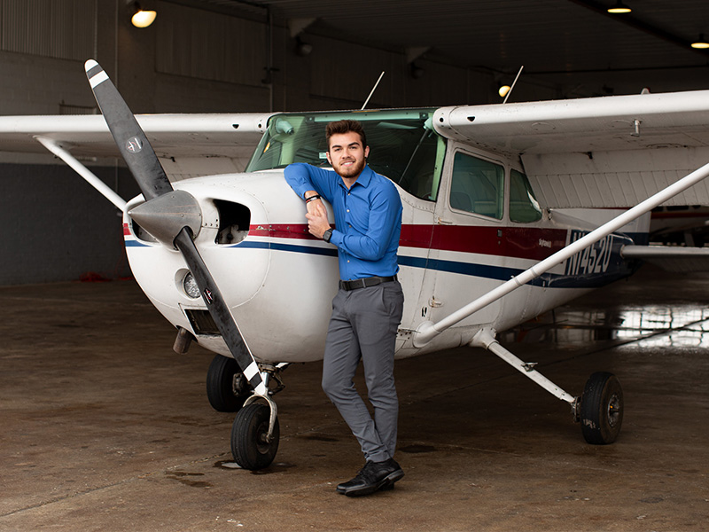 An aeronautics student at PennWest stands next to an airplane.