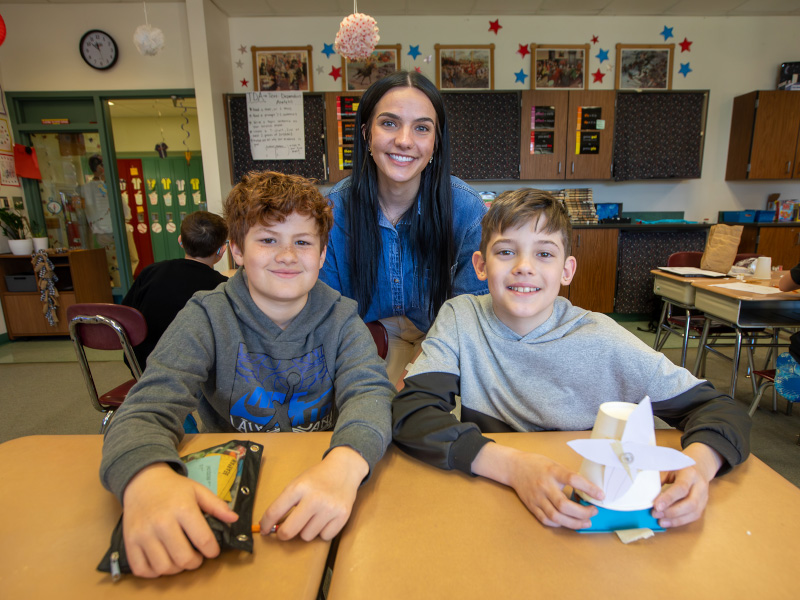 Student teacher poses with classroom students. 